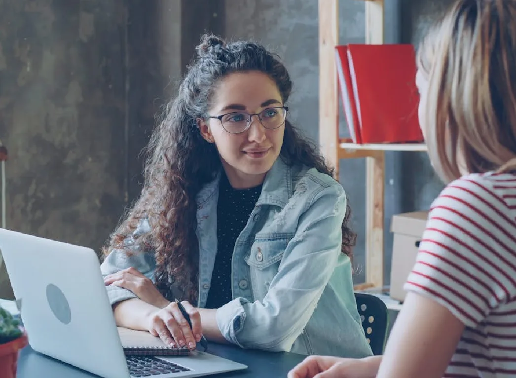 Two students sitting and proofreading their essay while discussing on ideas.